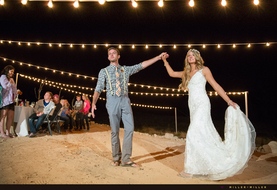 bride groom dancing under string lights beach